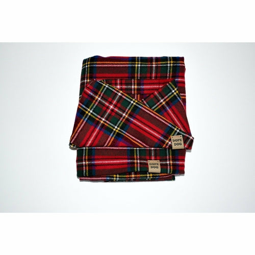 Folded red and green plaid blanket with a brand label on a white background